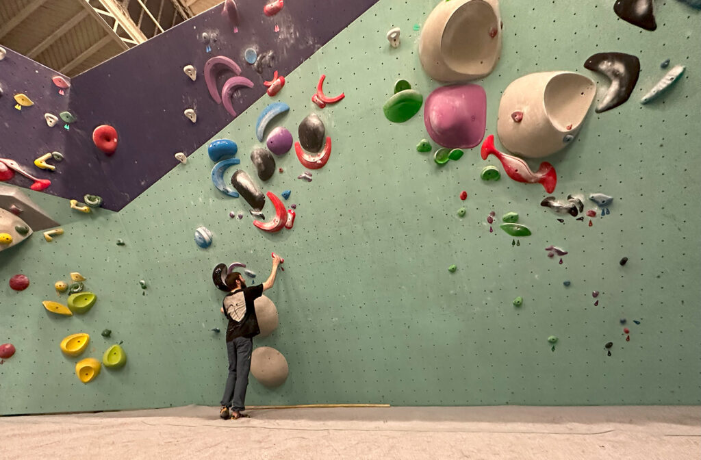 man at bottom of rock climbing wall